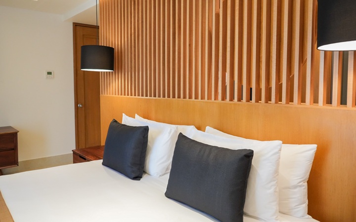 Primer plano de la cabecera del Scenic Studio que enmarca una cama King-size, acompañada de una mesa de noche a la medida y dos lámparas colgantes en Kadun Hotel Boutique.
