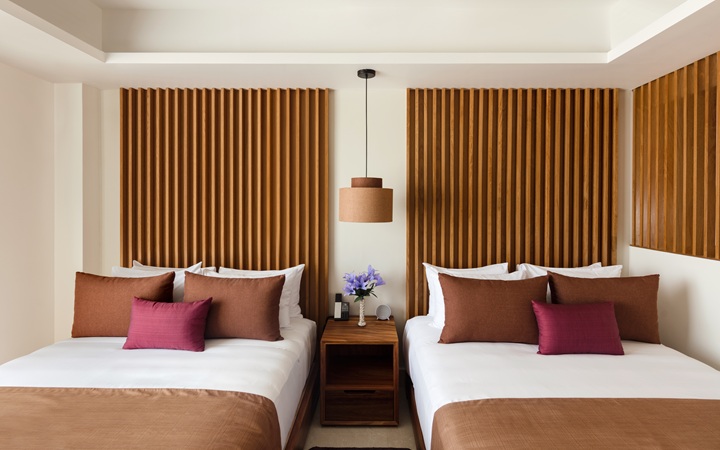 Diseño sofisticado de la habitación Studio con dos lujosas camas dobles, una mesa de noche de madera central y una lámpara de lectura a la medida en Kadun Hotel Boutique.
