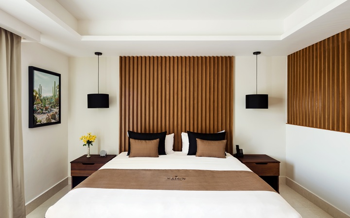 Studio de lujo minimalista con una confortable cama King-size flanqueada por mesas de noche de madera simétricas y elegantes lámparas de diseño en Kadun Hotel Boutique.