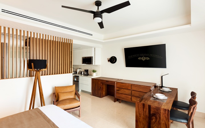 Comedor sofisticado y espacio de trabajo dentro de la suite de lujo, que muestra una mesa de comedor minimalista, un escritorio de trabajo exclusivo con silla y una smart TV en Kadun Hotel Boutique.