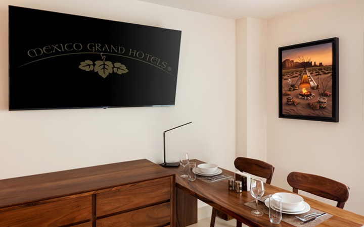 Área de comedor minimalista dentro de la suite studio de lujo, que muestra una mesa de madera contemporánea y una smart TV montada en la pared en Kadun Hotel Boutique.