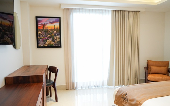 Suite de lujo con terraza privada que cuenta con un jacuzzi integrado, un escritorio de trabajo exclusivo de madera con silla y un cómodo sillón decorativo en Kadun Hotel Boutique.