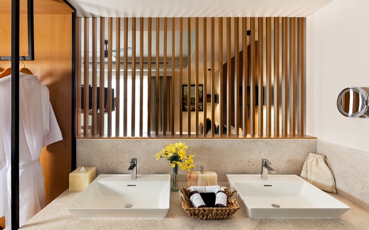 Perspectiva del baño de lujo que destaca los tocadores con lavabos dobles independientes y lujosas batas de baño premium en Kadun Hotel Boutique.